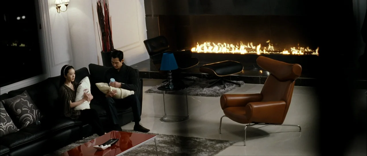The Housemaid (2010) (2010) movie still: wide — A modern, minimalist space with a horizontal fireplace wall and glossy tiled floors. A man and woman…