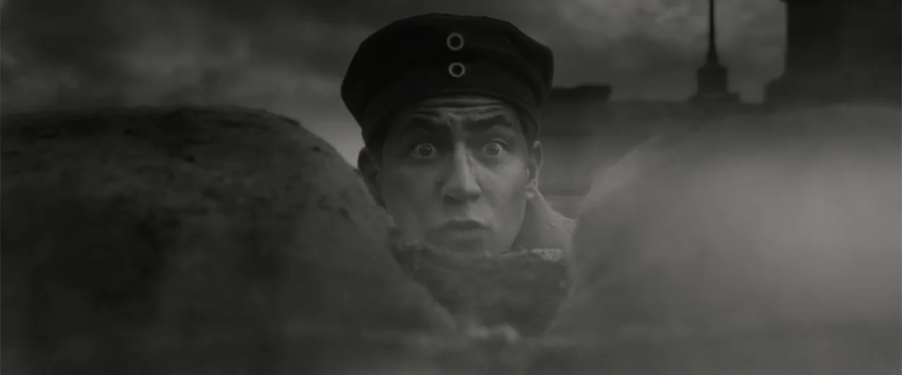 Death on the Nile (2022) movie still: closeup — A dark muddy trench with a thick, uneven dirt parapet edge. A young soldier peeks his face over the…