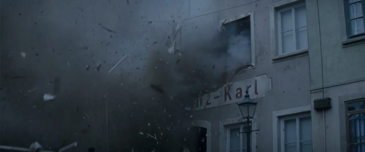 Fury (2014) movie still: wide — A stone building facade features a painted sign and windows obscured by a violent explosion. Massive amounts of dark…