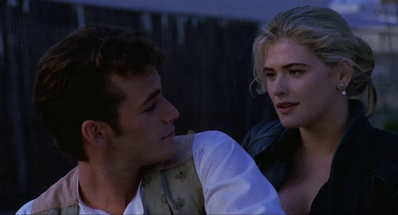 Buffy the Vampire Slayer (1992) movie still: medium — A dark outdoor space serves as the backdrop for two people in conversation. The man wears a…