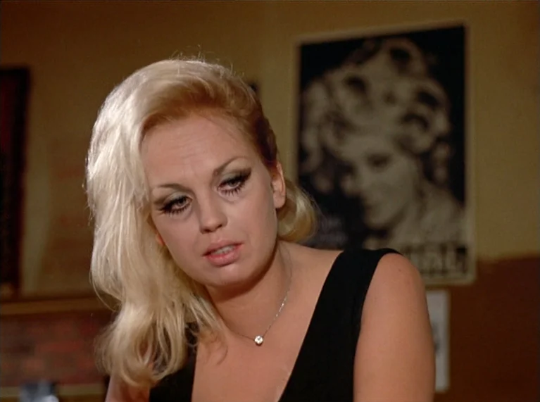 Ali: Fear Eats The Soul (1974) movie still: closeup — An indoor space features a wall adorned with a framed black and white photograph. A blonde…