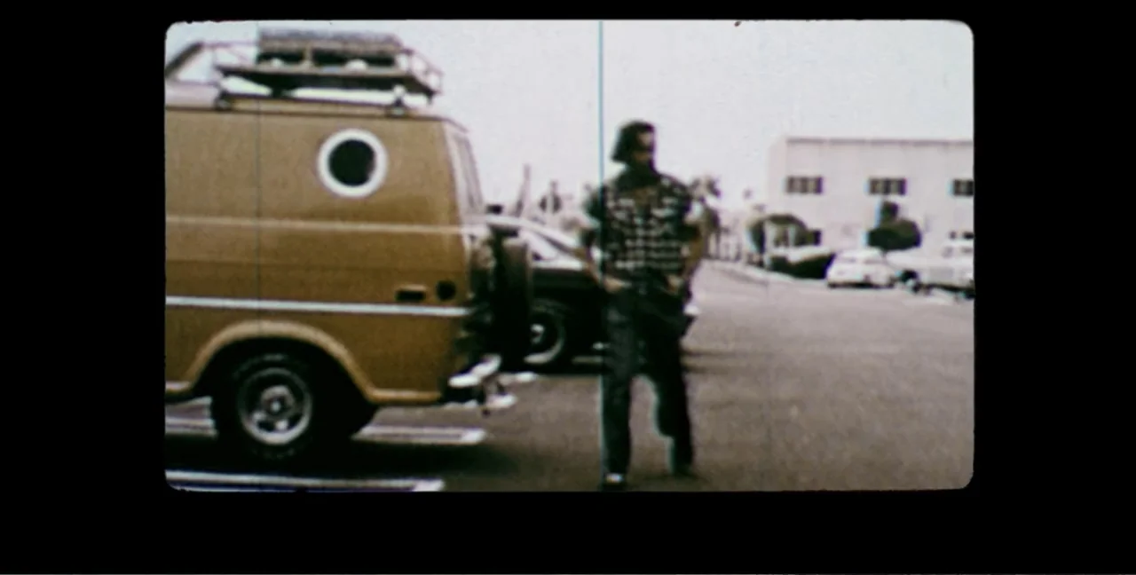 Alien Abduction: Travis Walton (2022) movie still: fullbody — An asphalt parking lot sits beside a tan van with a roof rack. A man walks forward…