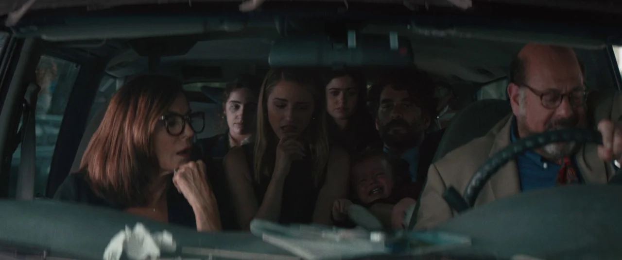 Shiva Baby (2020) movie still: medium — The interior of a car filled with six people during daylight travel. A man drives while the other passengers…