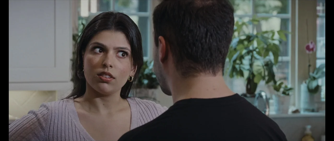 Ordinary Things (2001) movie still: medium — A residential kitchen features a window in the background with greenery visible outside. A woman faces…