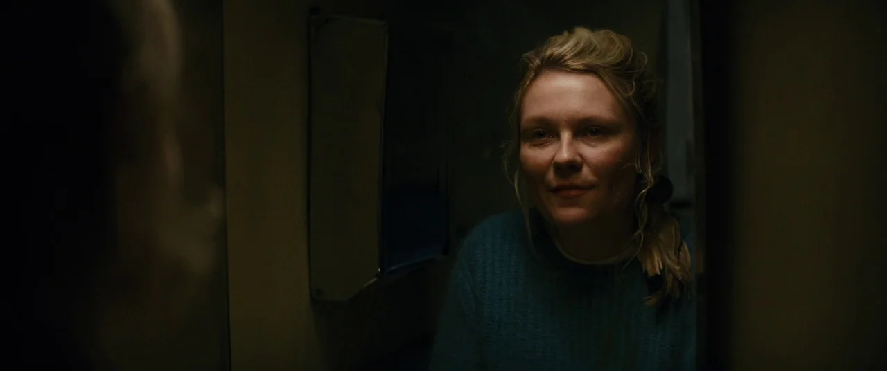 Midnight Special (2016) movie still: closeup — A dimly lit, narrow washroom features a reflective surface in a dark space. A woman stares into the…