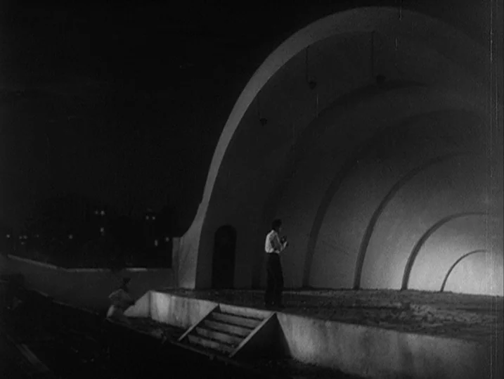 One Wonderful Sunday (1947) movie still: wide — A large, semi-circular concrete bandshell sits empty in the darkness of the night. A single man…