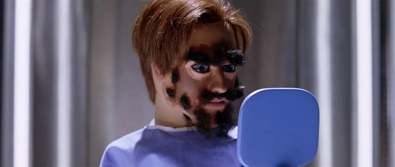 Team America: World Police movie still: closeup — A clinical space is defined by cool vertical light sources in the background. A puppet character…