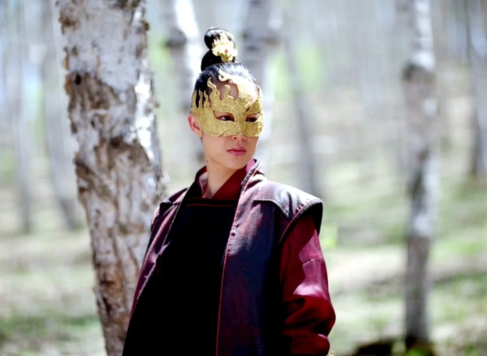 The Assassin (2015) movie still: medium — A dense grove of white-barked birch trees forms a blurred background for a subject. A woman wears a…