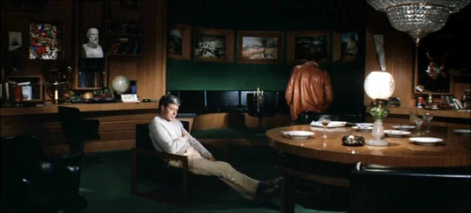 Solaris (1972) movie still: medium — A wood-paneled room decorated with framed paintings and a white bust on a shelf. A man sits in a low chair…