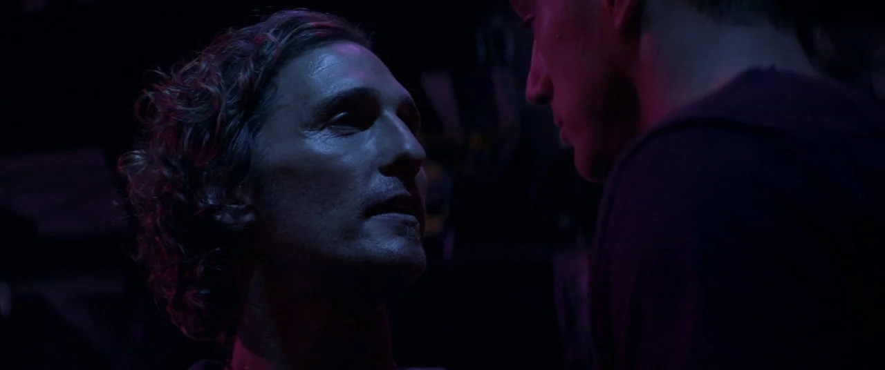 Magic Mike (2012) movie still: medium — A dimly lit club interior characterized by dark shadows and purple neon light. Two men face each other in…