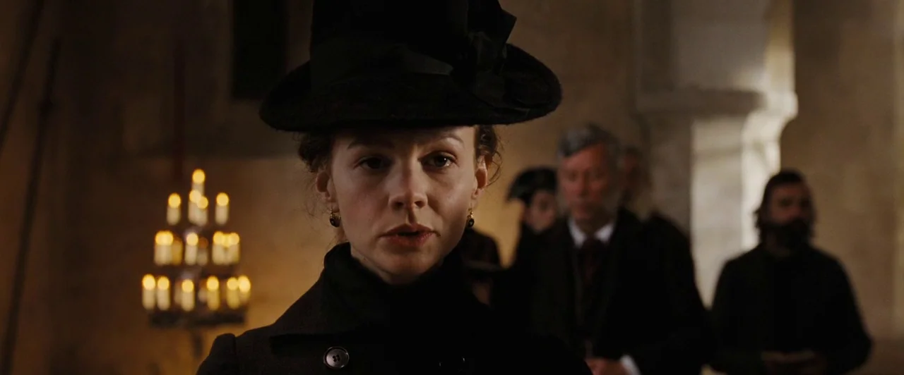Far from the Madding Crowd (2015) movie still: closeup — The interior of a dim stone building features stone pillars and warm candlelight. A woman…