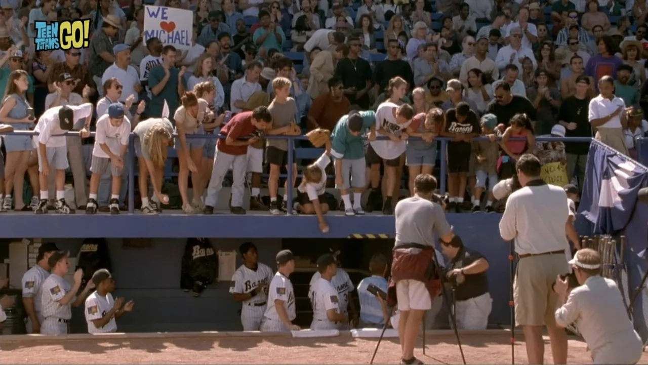 Teen Titans Go! To the Movies (2018) movie still: wide — A crowded baseball stadium features fans leaning over the railing of a blue dugout. Players…