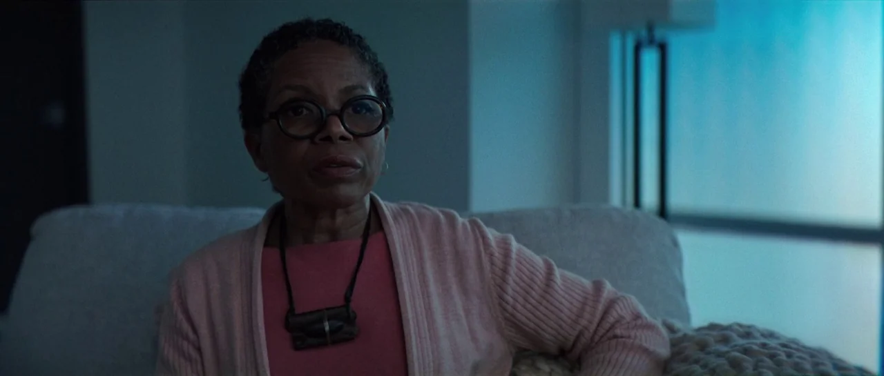 The Boogeyman (2023) movie still: medium — An interior space features a woman seated on a textured white sofa at night. Large windows with…