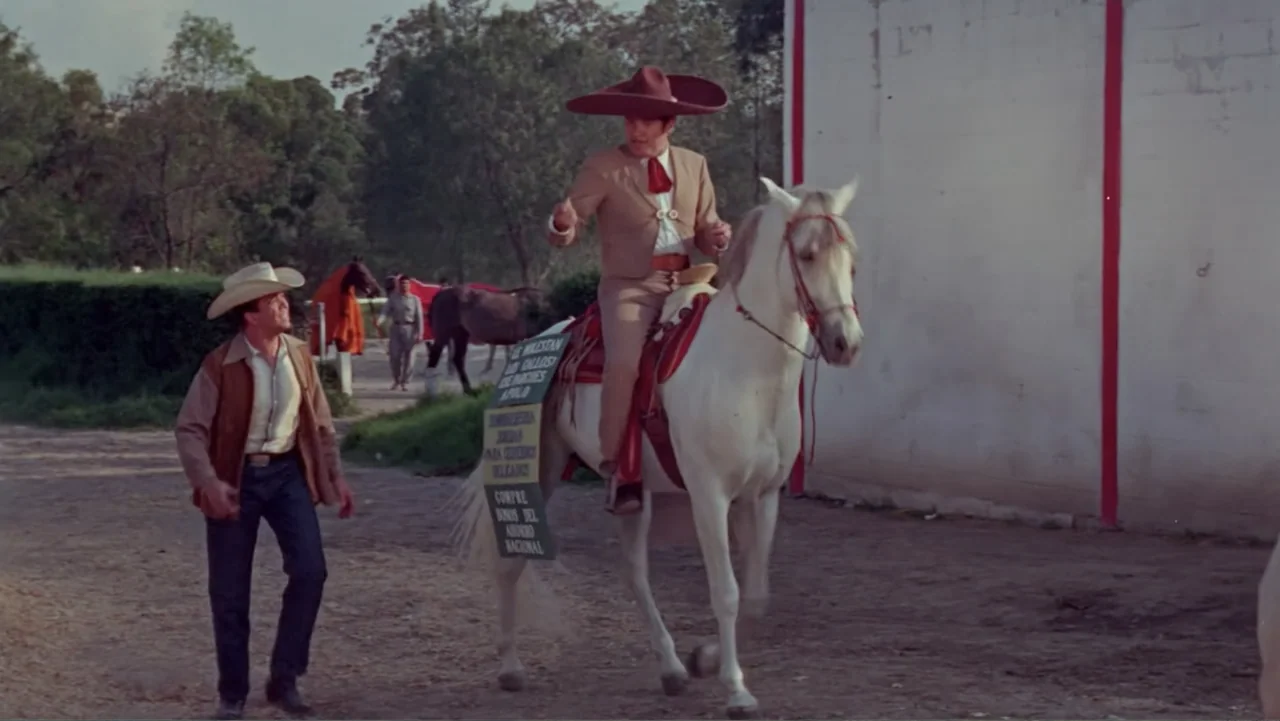 Los Dos Rivales (1966) movie still: fullbody — A dirt path runs alongside a white wall in an outdoor open area. A man rides a white horse while…