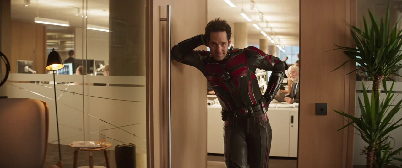 Ant-Man and the Wasp: Quantumania (2023) movie still: medium — A modern corporate workspace featuring wood paneling, glass partitions, and desks in…