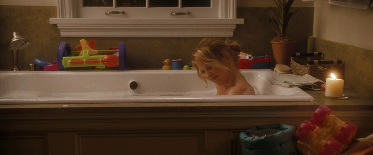 Life As We Know It (2010) movie still: medium — A residential bathroom features a large porcelain tub filled with bath toys and bubbles. A woman…