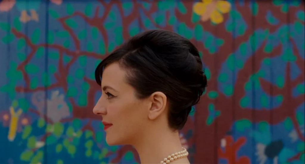 Heartbeats (Les Amours Imaginaires) (2010) movie still: closeup — A colorful wall mural featuring stylized trees and butterflies serves as a…