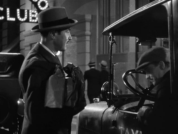 The Roaring Twenties (1939) movie still: medium — An urban night scene features a man standing beside a vintage taxi cab. The brightly lit 'CLUB'…