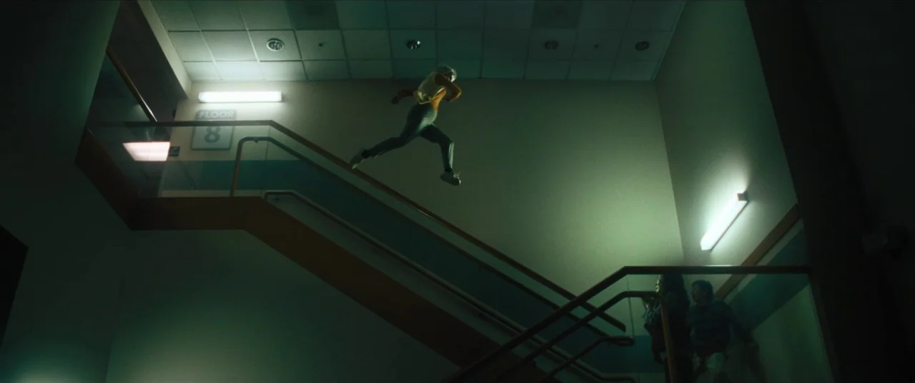 Everything Everywhere All At Once (2022) movie still: wide — A modern, sterile hospital stairwell with beige walls, a tile ceiling, and metal…