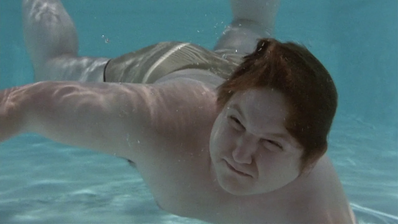 Pee-Wee’s Big Adventure (1985) movie still: medium — An underwater perspective of a swimming pool with bright, teal-tinted water. A young man with…