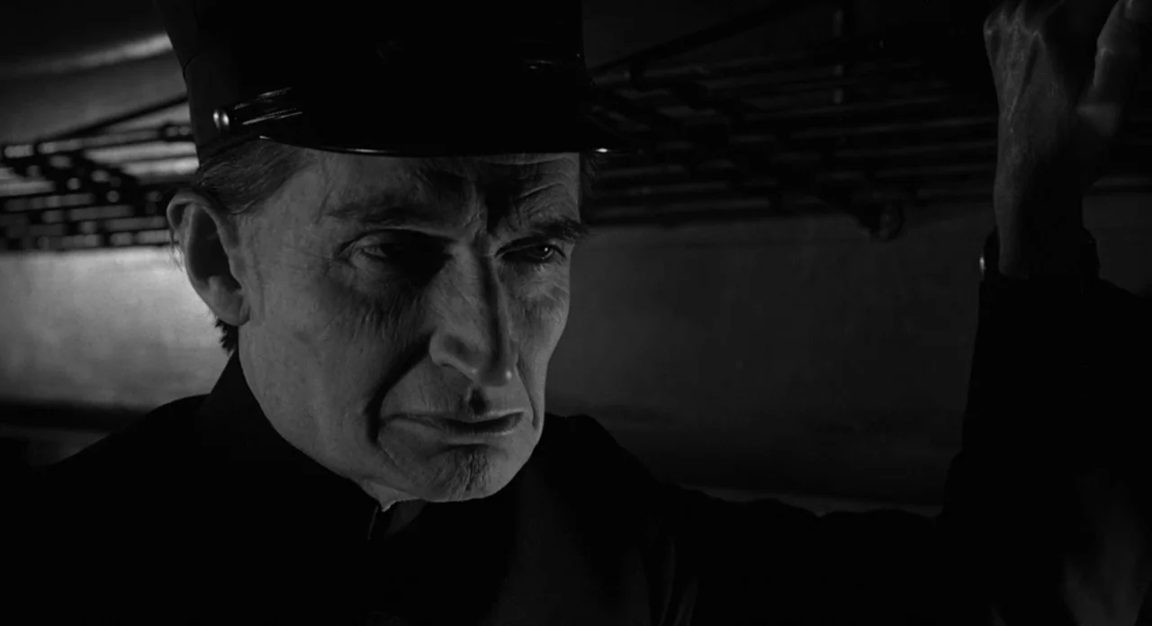 Stardust Memories (1980) movie still: closeup — A dimly lit, cramped compartment with dark overhead luggage racks and metal walls. An older man in a…