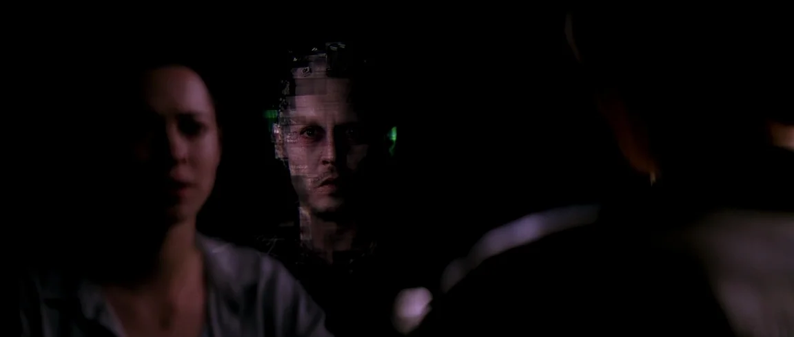 Transcendence (2014) movie still: medium — A dark space features a woman in the foreground and a man centered behind her. The man's face is…