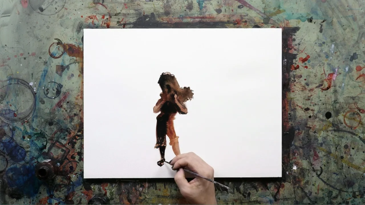 Between the World and Me (2020) movie still: closeup — A white canvas sits on a work surface covered in dried paint splatters. A hand holds a brush…