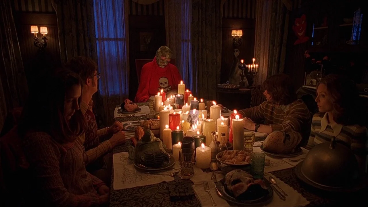 House of 1000 Corpses (2003) movie still: medium — A dark dining room with vertical striped wallpaper lit by many candles on the table. Five people…