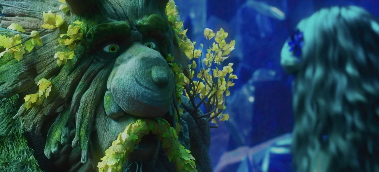 Mavka: The Forest Song (2023) movie still: closeup — A dark, textured woodland area featuring dense vegetation and dim, blue lighting. A tree…