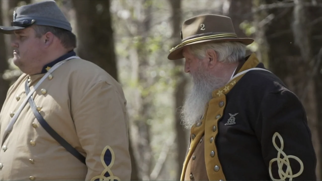 Kill Cavalry (2021) movie still: medium — A dense patch of woodland serves as the setting for two historical figures standing. The men wear Civil…