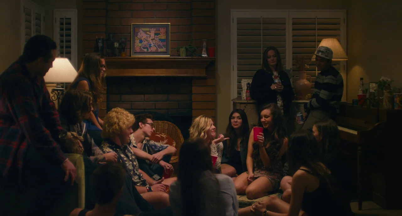 Palo Alto (2013) movie still: wide — A group of young adults congregates in a dimly lit living room at night. They are seated in a semi-circle on…