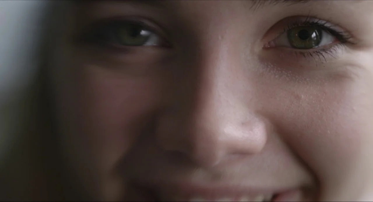 The Falling movie still: closeup — An extreme close-up of a young person's face showing skin texture and eyes. The subject is looking directly into…
