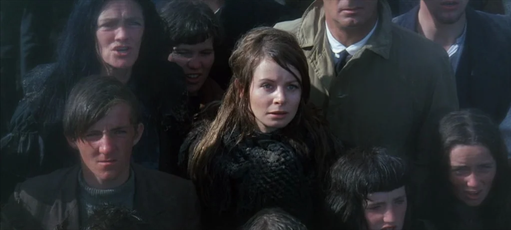 Ryan’s Daughter (1970) movie still: medium — A dense group of people stand outdoors in overcast weather conditions. The subjects look forward with…