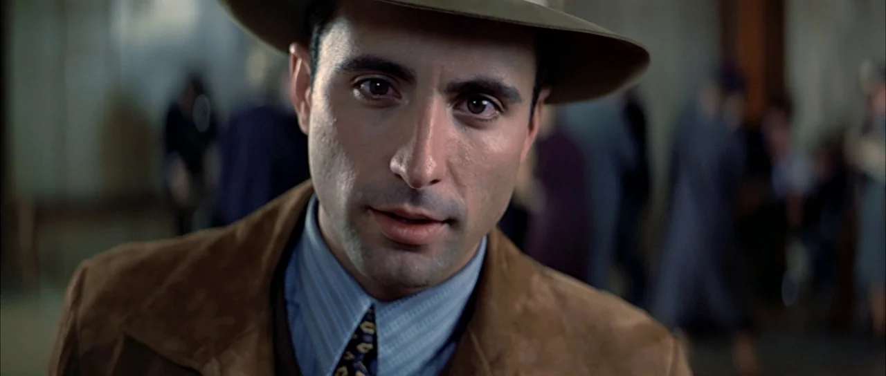 The Untouchables (1987) movie still: closeup — An interior space with blurred figures in the background suggests a busy public location. A man…