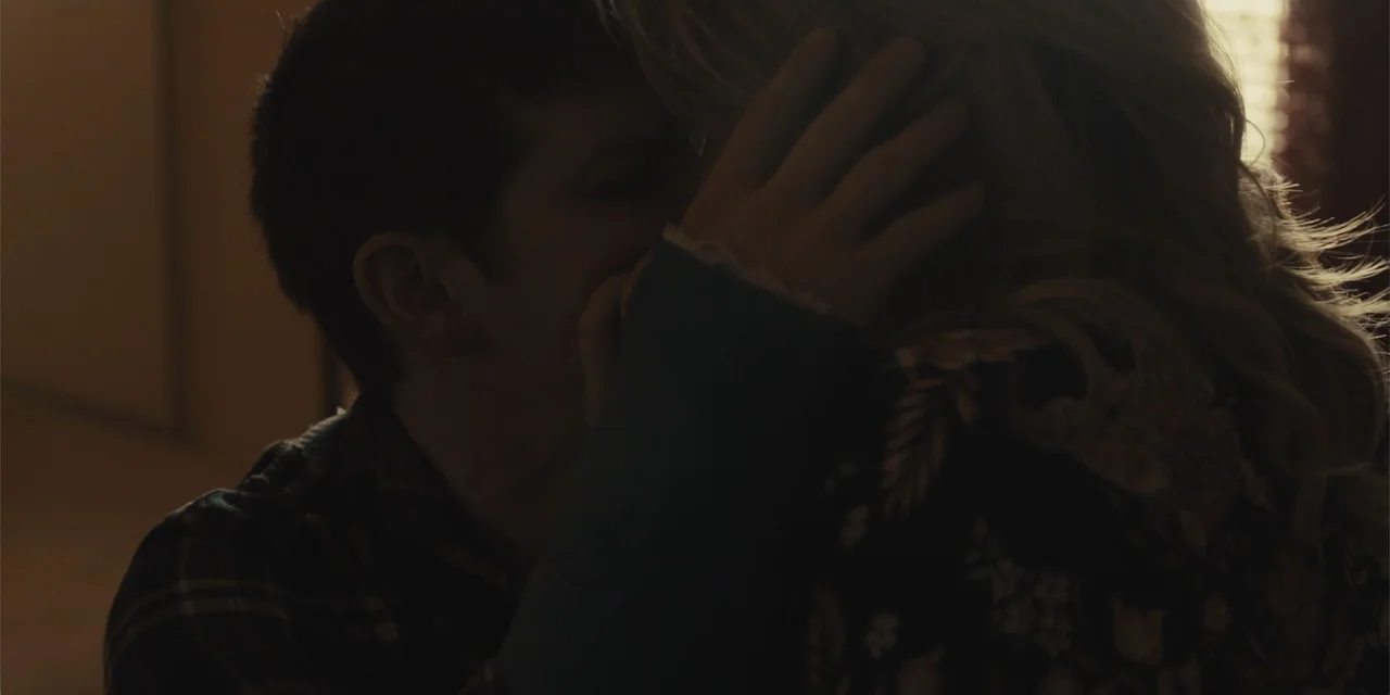 All Roads to Pearla (2019) movie still: closeup — A dimly lit indoor space with low-key illumination coming from a nearby window. A man and a woman…