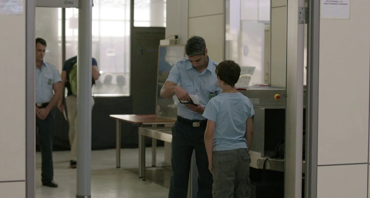 Before Midnight (2013) movie still: medium — An airport security station features a metal detector frame and an X-ray scanner unit. A security…