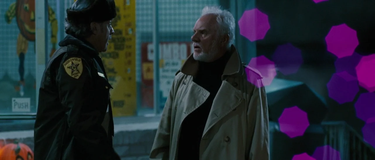 Halloween (2007) movie still: medium — A glass fronted building displays holiday decorations at night under dim ambient lighting. A police officer…