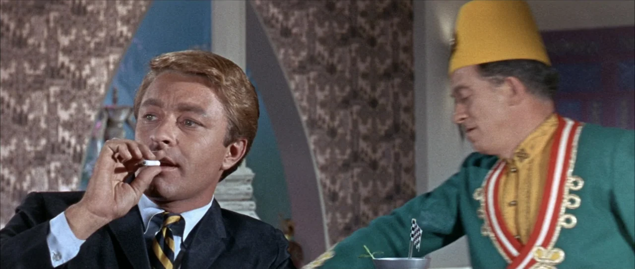 Clambake (1967) movie still: medium — A 1960s indoor space features decorative patterned wallpaper and an archway detail. Two men sit together while…