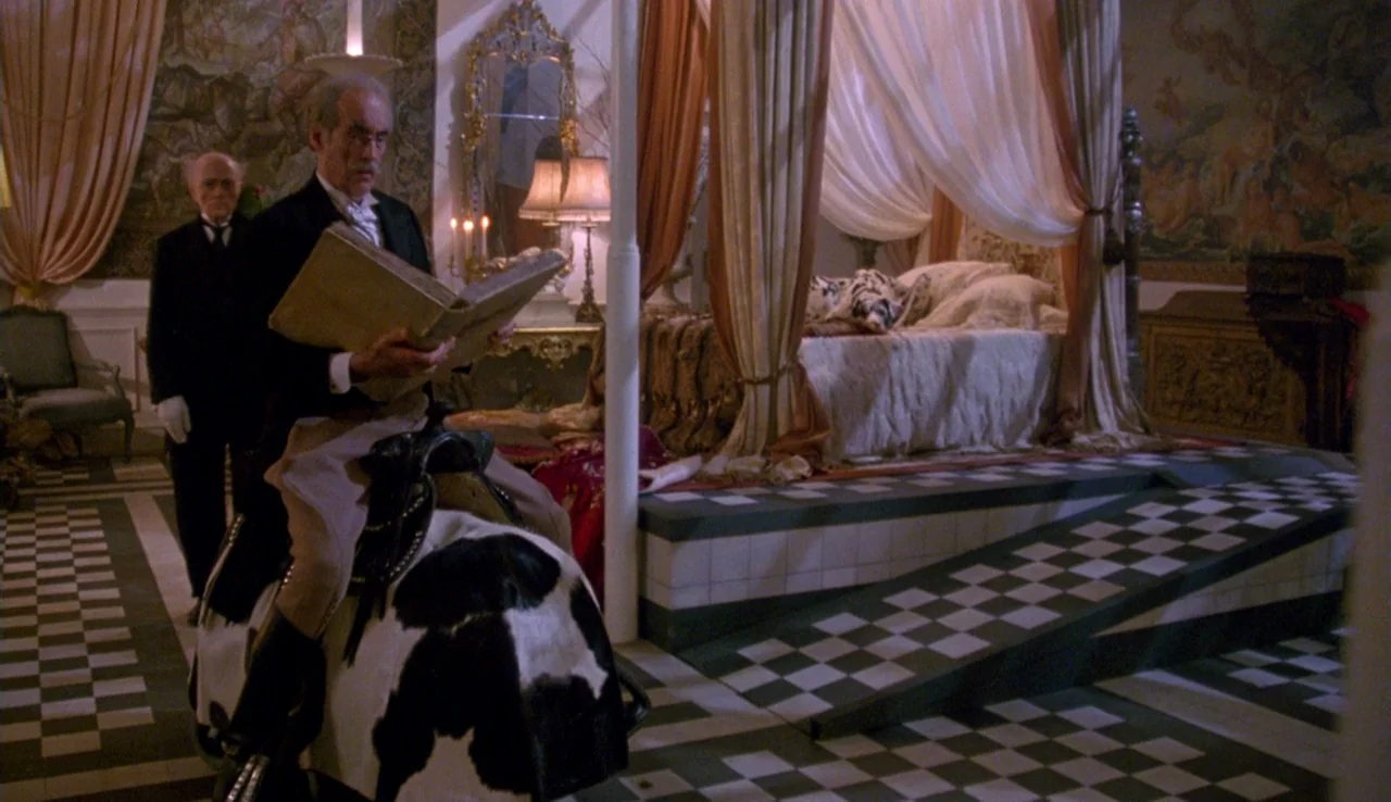 The Rainbow Thief (1990) movie still: fullbody — An opulent room features a checkered floor and a large draped four-poster bed. A man in formal…