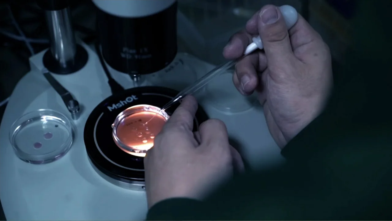 Almost Human: Rise of the Apes (2022) movie still: closeup — A laboratory setting features a specialized microscope stage illuminated with a bright…