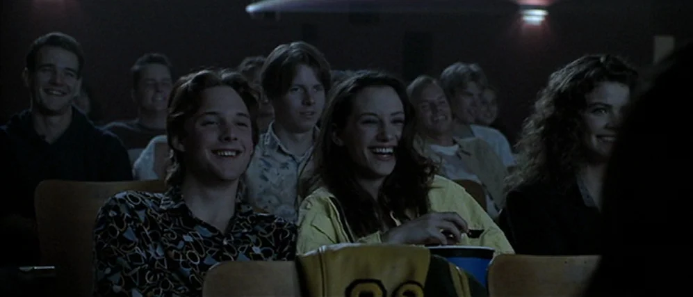 Apt Pupil (1998) movie still: medium — A group of teenagers sits in a dark, multi-row auditorium. They watch a movie while lit by the illumination…