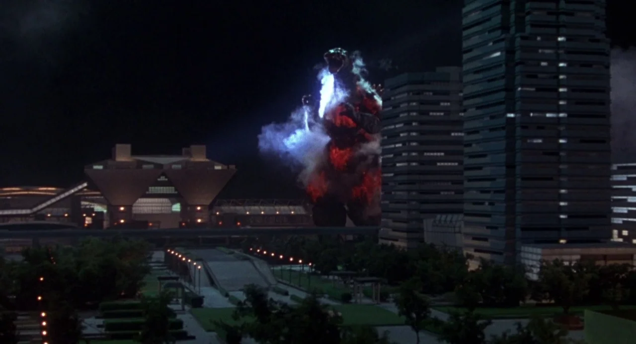 Godzilla vs. Destoroyah (1995) movie still: wide — A modern urban skyline at night features tall office buildings and paved public walkways. A giant…