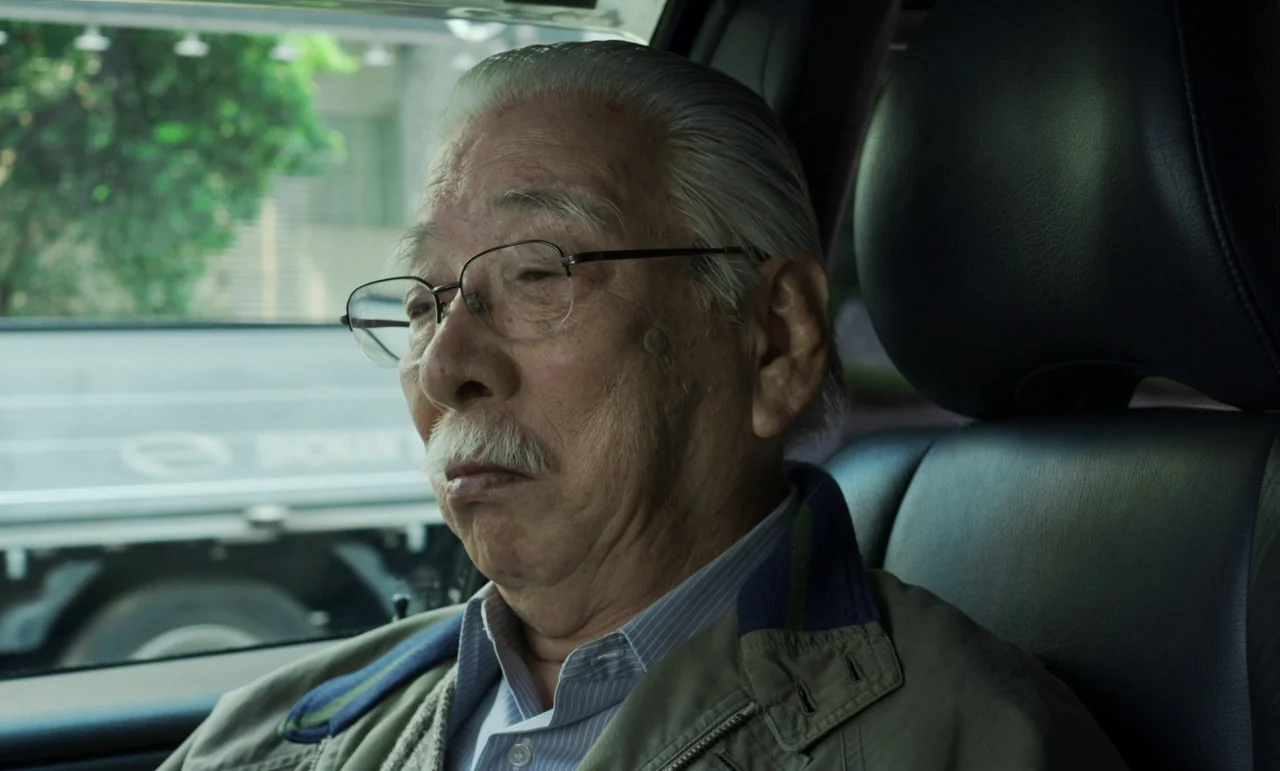 Like Someone In Love (2012) movie still: closeup — The interior of a passenger car with black leather seating and tinted windows. An elderly East…