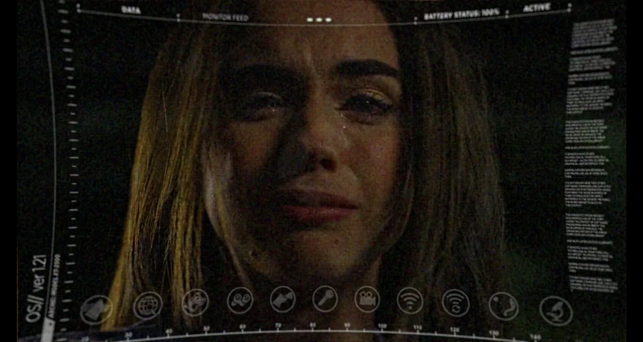 A.R.C.H.I.E. (2016) movie still: closeup — The frame displays a digital heads-up display interface overlaid on a dark, unknown environment. A young…