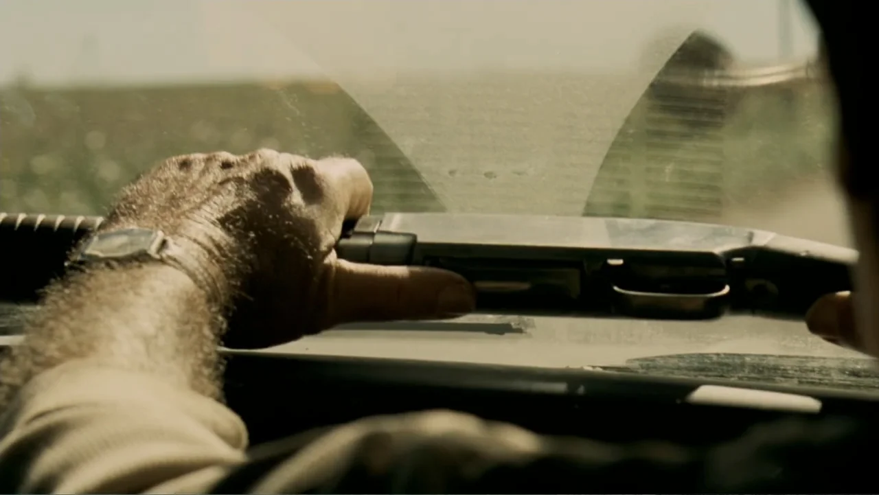 The Texas Chainsaw Massacre: The Beginning (2006) movie still: closeup — A view from inside a car looking out through a dusty windshield. A man…