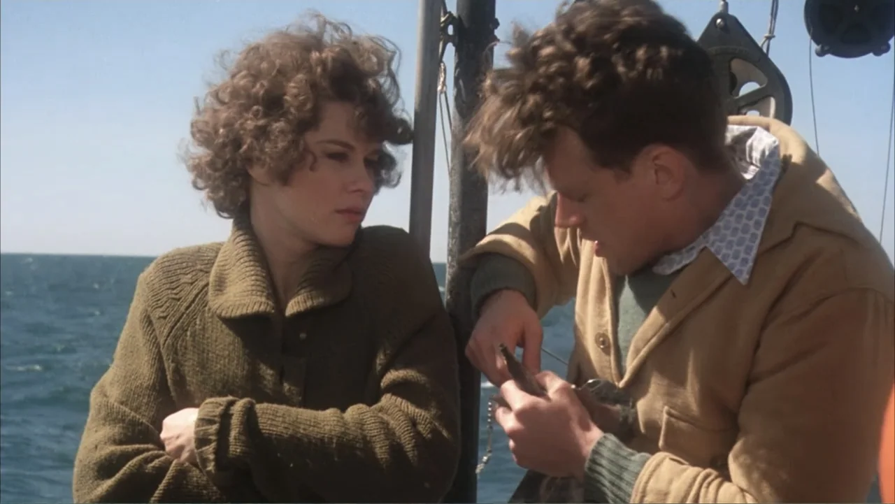 One Flew Over the Cuckoo's Nest (1975) movie still: medium — Two people stand together on a boat deck surrounded by open water. A man holds a small…