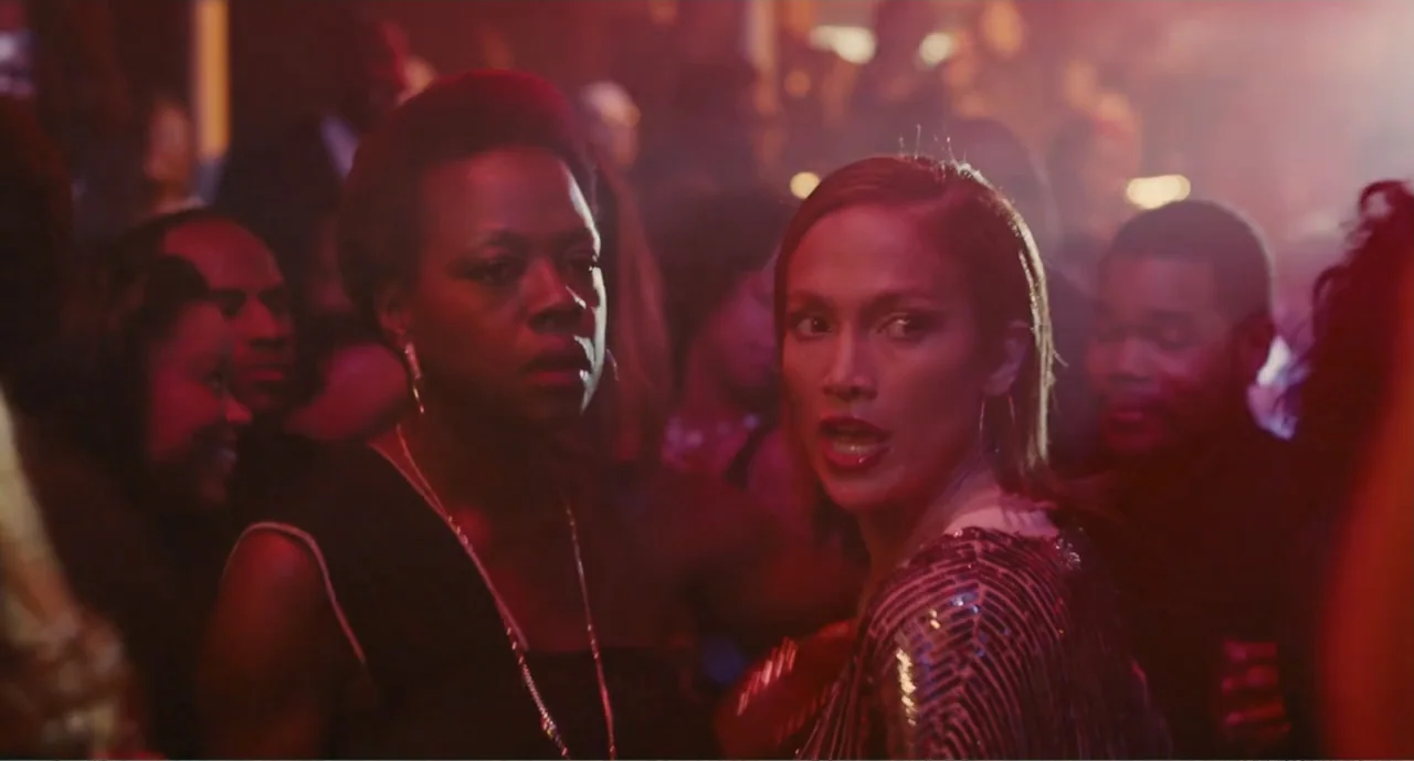 Lila & Eve (2015) movie still: medium — A crowded nightclub interior features red lighting and blurred figures in the background. Two women stand in…