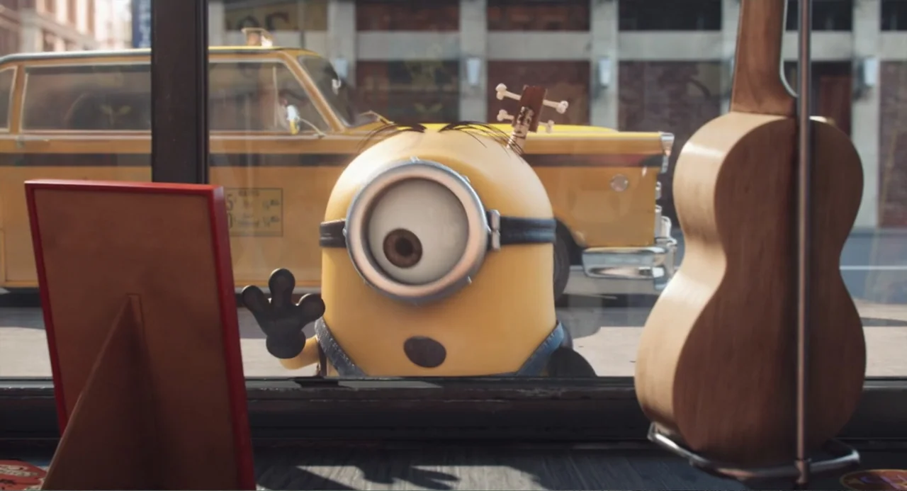 Minions (2015) movie still: medium — A yellow cartoon creature looks through the glass of a storefront display window. The creature is waving with…