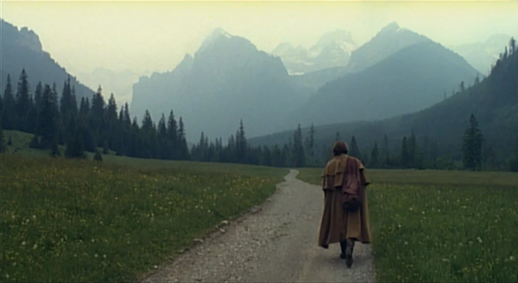 Nosferatu the Vampyre (Nosferatu Phantom Der Nacht) (1979) movie still: wide — A gravel path winds through a grassy alpine valley toward distant…