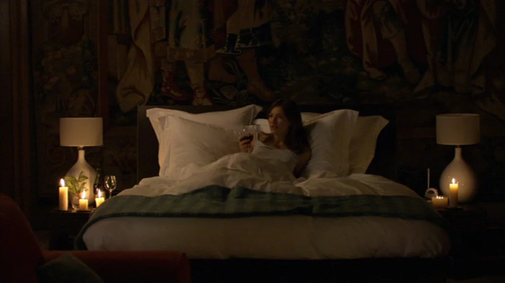 A Cock and Bull Story (2005) movie still: medium — A dark, candlelit room features a large bed positioned before a decorative antique tapestry. A…
